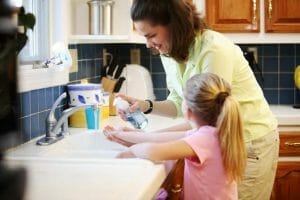 woman and daughter washing at kitchen sink